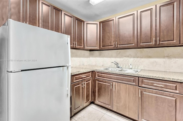 kitchen featuring light tile patterned flooring, decorative backsplash, white refrigerator, and sink