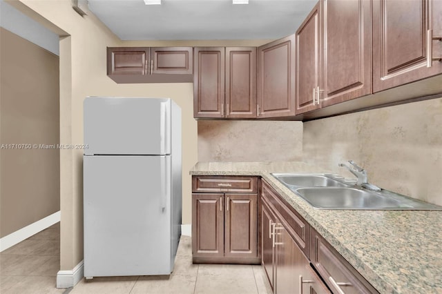 kitchen featuring backsplash, white fridge, light tile patterned flooring, and sink