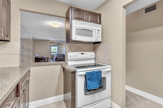 kitchen featuring kitchen peninsula, white appliances, a textured ceiling, and light tile patterned floors