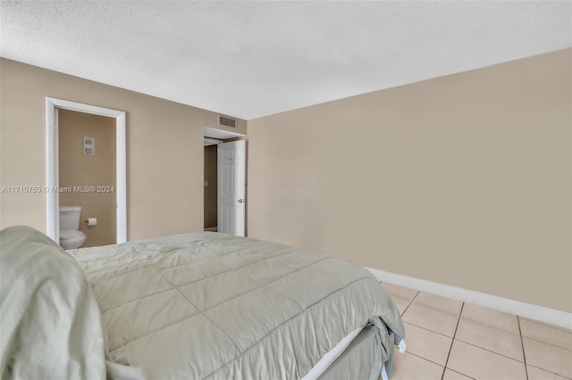 bedroom featuring a textured ceiling, connected bathroom, and light tile patterned flooring