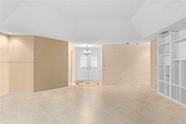 tiled empty room featuring an inviting chandelier