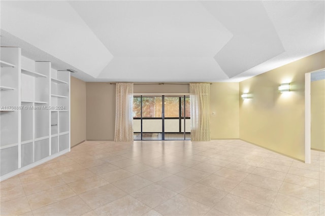 tiled spare room featuring a raised ceiling