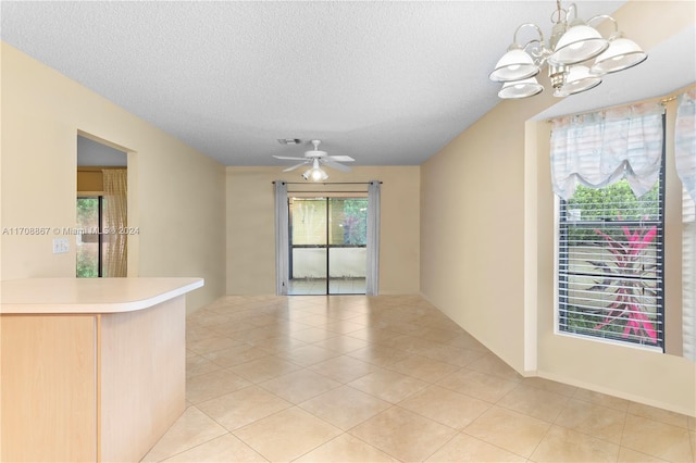 interior space with ceiling fan with notable chandelier, light tile patterned floors, and a textured ceiling