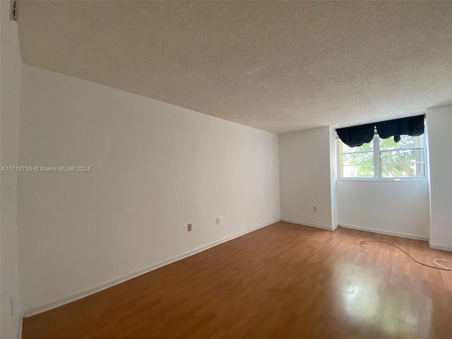 unfurnished room with hardwood / wood-style floors and a textured ceiling