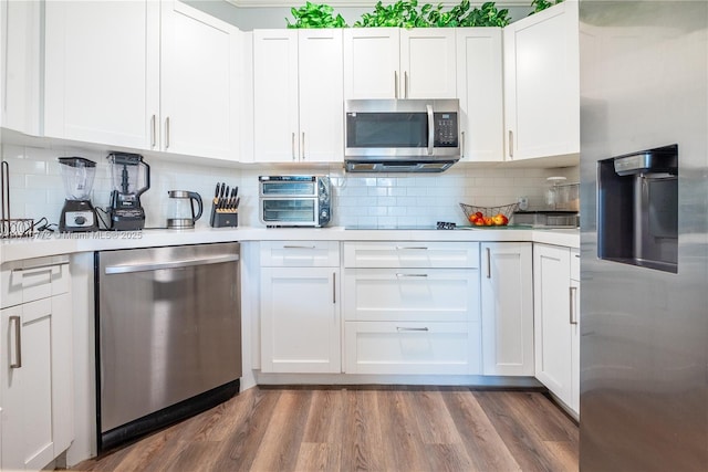 kitchen with decorative backsplash, dark hardwood / wood-style floors, white cabinetry, and stainless steel appliances