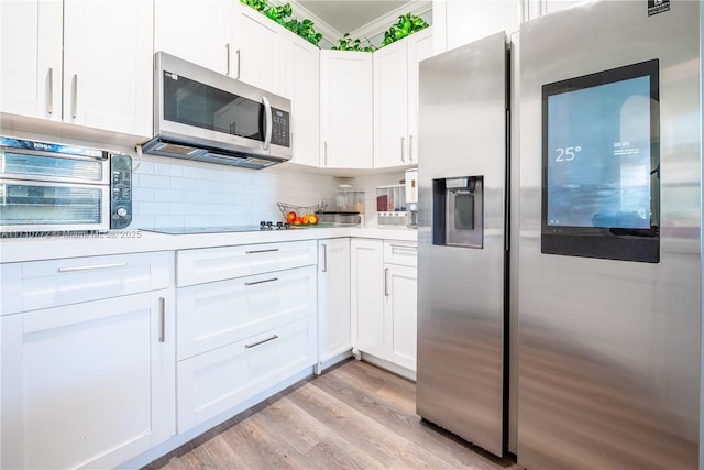 kitchen with tasteful backsplash, white cabinetry, stainless steel appliances, and light wood-type flooring