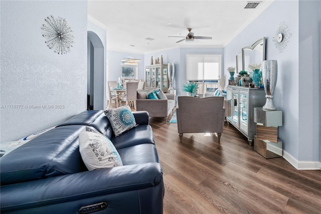 living room featuring plenty of natural light, ceiling fan, ornamental molding, and dark wood-type flooring