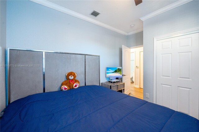 bedroom featuring hardwood / wood-style flooring, ceiling fan, and ornamental molding