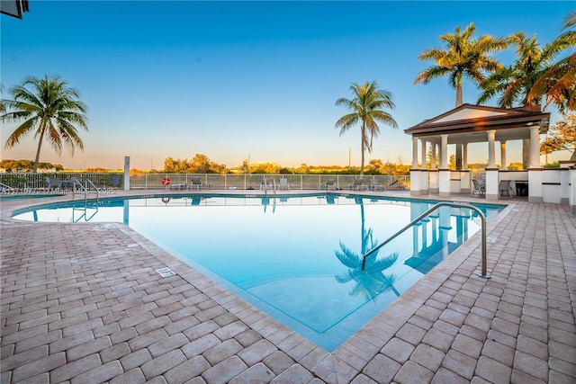 pool at dusk featuring a patio area