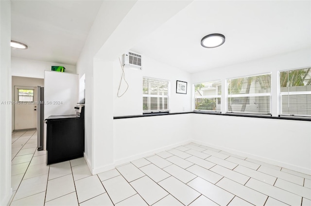 interior space with a wall mounted air conditioner, light tile patterned floors, a wealth of natural light, and vaulted ceiling