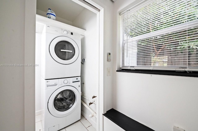 laundry area featuring light tile patterned flooring and stacked washer and dryer