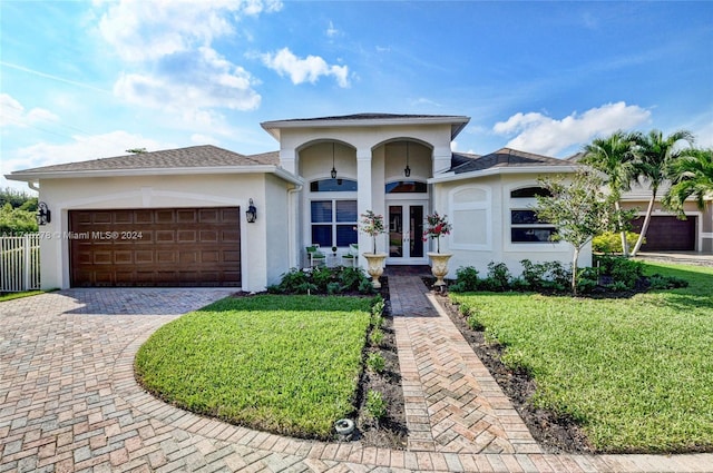 view of front of property with french doors, a front lawn, and a garage