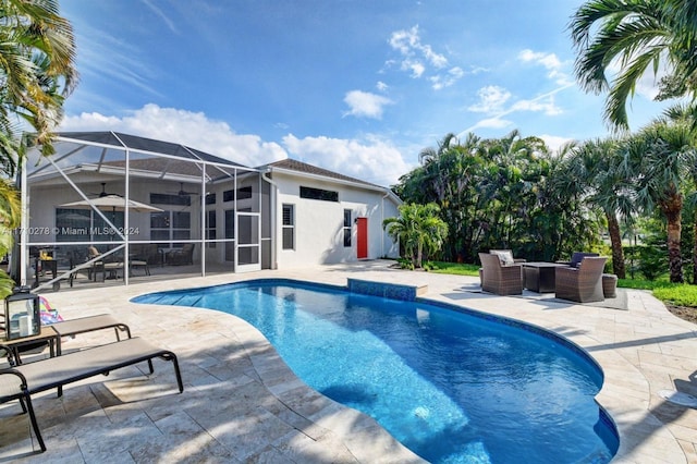 view of swimming pool featuring ceiling fan, a lanai, and a patio