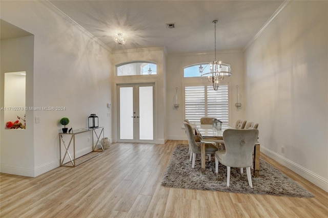 dining space featuring french doors, light hardwood / wood-style floors, a notable chandelier, and ornamental molding