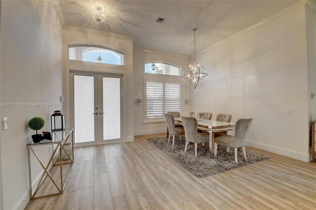 dining space with french doors, light hardwood / wood-style floors, ornamental molding, and a notable chandelier