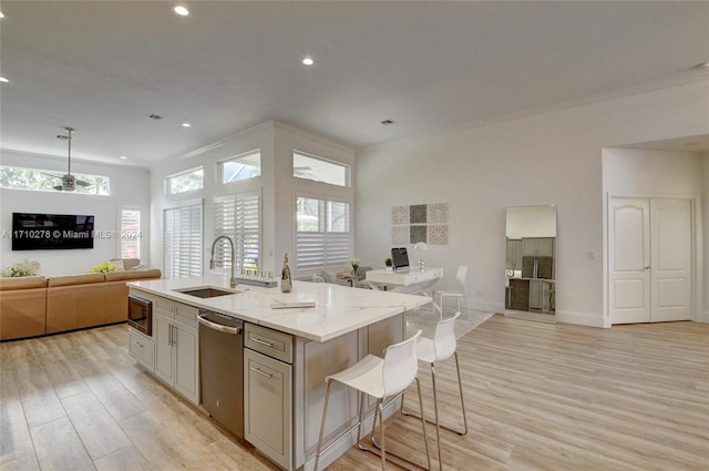 kitchen featuring light stone counters, stainless steel appliances, sink, a center island with sink, and light hardwood / wood-style flooring