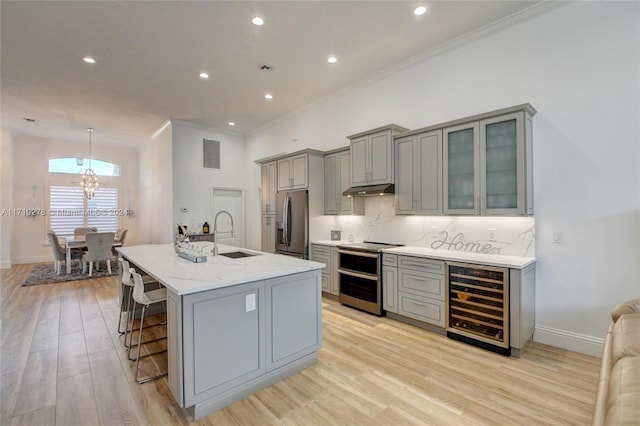 kitchen featuring wine cooler, a breakfast bar area, gray cabinets, decorative light fixtures, and stainless steel appliances