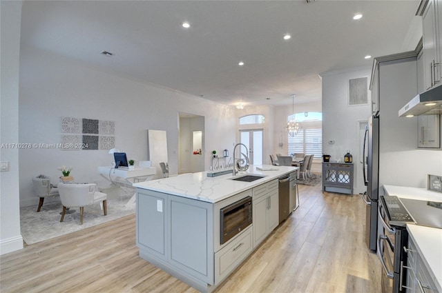 kitchen with sink, light hardwood / wood-style flooring, gray cabinets, an island with sink, and stainless steel appliances