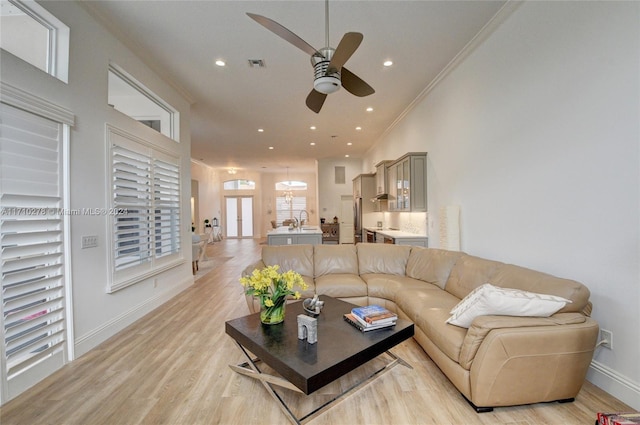 living room featuring light hardwood / wood-style floors, ceiling fan, and ornamental molding