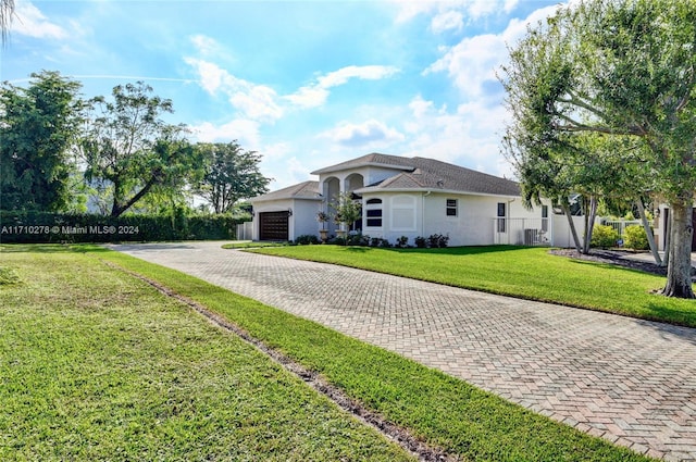 single story home featuring cooling unit, a garage, and a front lawn