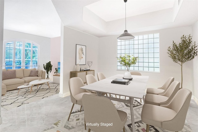 dining space featuring light tile patterned floors and a tray ceiling