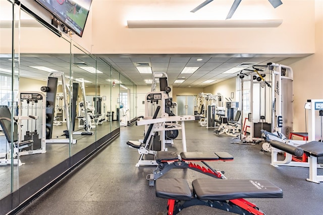 exercise room with a paneled ceiling and a healthy amount of sunlight