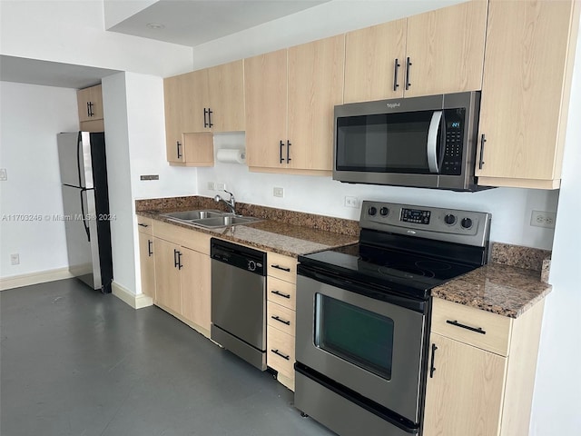 kitchen with dark stone countertops, light brown cabinetry, stainless steel appliances, and sink