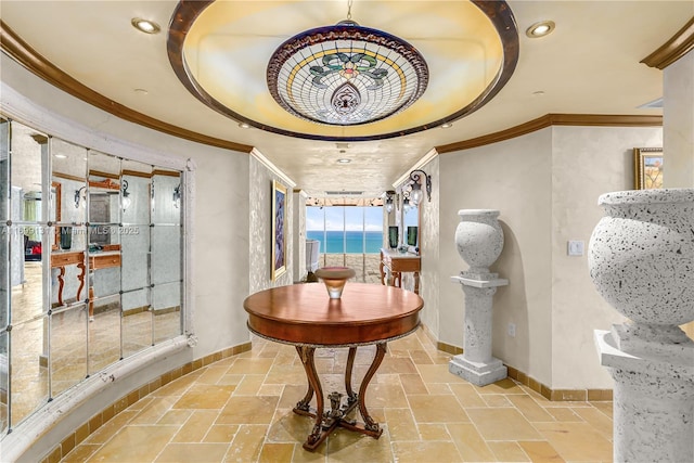 hallway featuring ornamental molding, a water view, and a tray ceiling