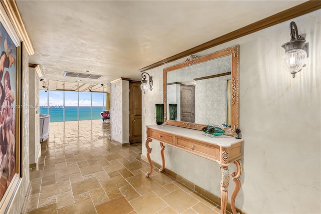 hall with floor to ceiling windows, a water view, and crown molding