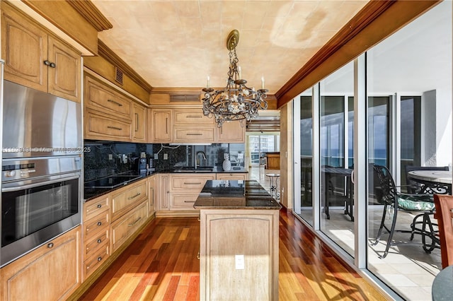 kitchen featuring black stovetop, light hardwood / wood-style flooring, tasteful backsplash, decorative light fixtures, and a kitchen island