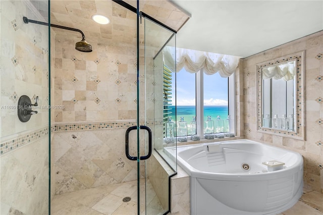 bathroom with separate shower and tub, a water view, and tile walls