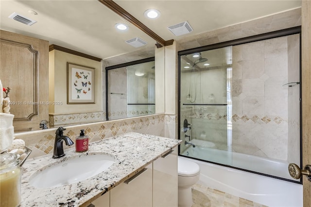 full bathroom featuring vanity, bath / shower combo with glass door, tile walls, and toilet