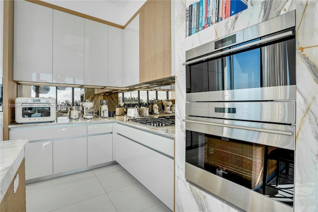 kitchen featuring white cabinets, light tile patterned floors, and stainless steel appliances