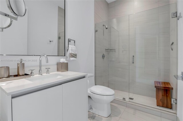 bathroom featuring tile patterned floors, vanity, toilet, and a shower with shower door