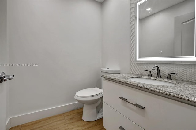 bathroom with hardwood / wood-style floors, vanity, toilet, and backsplash