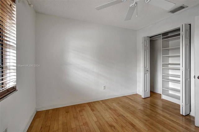 unfurnished bedroom with hardwood / wood-style flooring, ceiling fan, a textured ceiling, and a closet