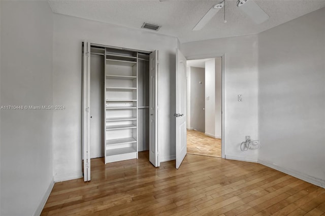 unfurnished bedroom featuring ceiling fan, wood-type flooring, a textured ceiling, and a closet