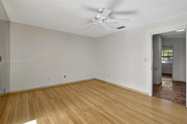 empty room with a textured ceiling, light wood-type flooring, and ceiling fan