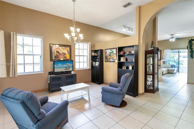 tiled living room with lofted ceiling, rail lighting, a healthy amount of sunlight, and ceiling fan with notable chandelier