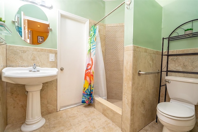 bathroom with tile patterned floors, curtained shower, tile walls, and toilet