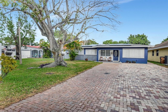 ranch-style house with a front yard and solar panels