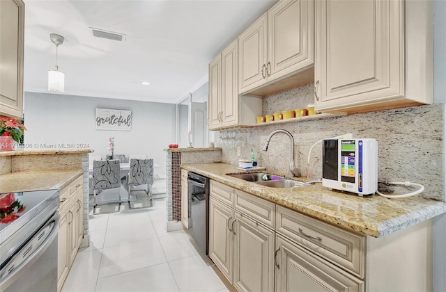 kitchen featuring sink, decorative light fixtures, cream cabinetry, black dishwasher, and light tile patterned flooring