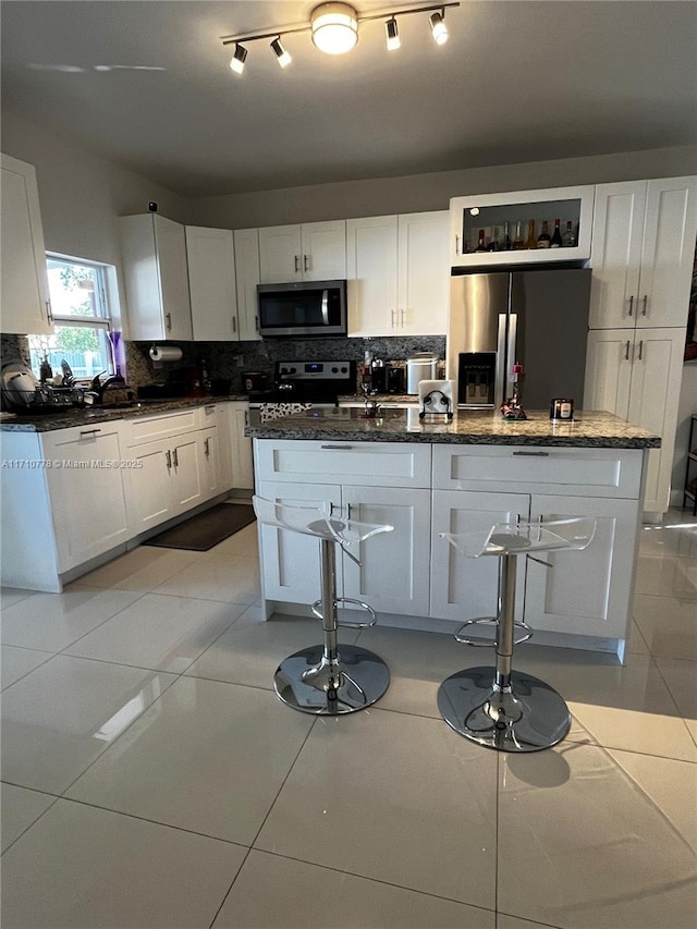 kitchen with white cabinets, a kitchen breakfast bar, a kitchen island, and stainless steel appliances