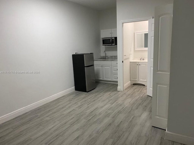 interior space with sink, white cabinets, light wood-type flooring, and appliances with stainless steel finishes