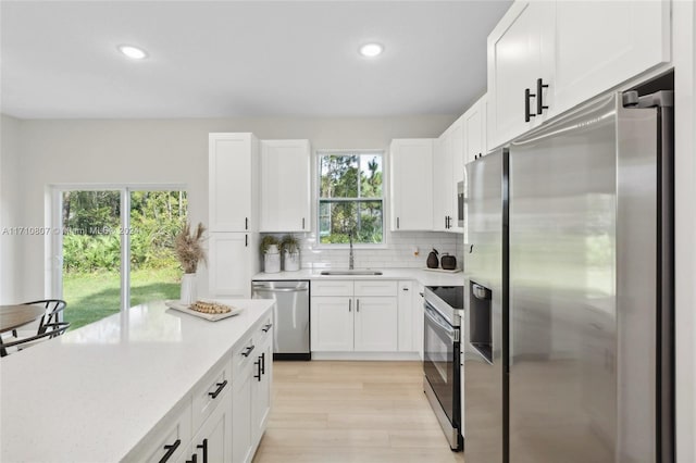 kitchen with appliances with stainless steel finishes, light hardwood / wood-style flooring, a healthy amount of sunlight, and sink