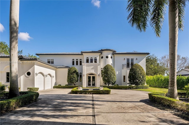 mediterranean / spanish-style home featuring a garage, a balcony, and french doors