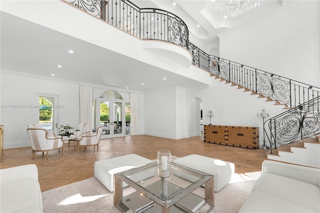 living room featuring light parquet floors, a towering ceiling, ornamental molding, and french doors