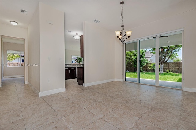 empty room featuring light tile patterned floors and an inviting chandelier