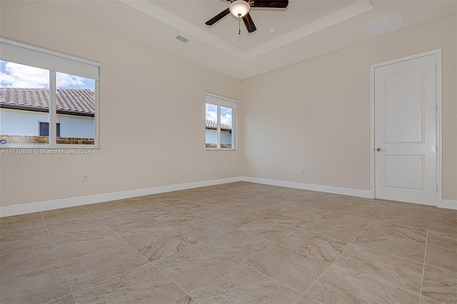 unfurnished room featuring a tray ceiling, a wealth of natural light, and ceiling fan