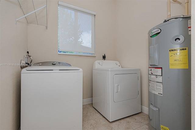 clothes washing area featuring light tile patterned flooring, washer and clothes dryer, and water heater